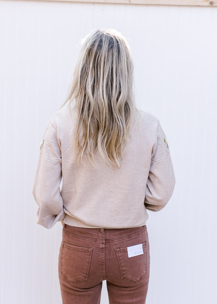Back view of Model wearing a beige sweater with long sleeves and round neck.