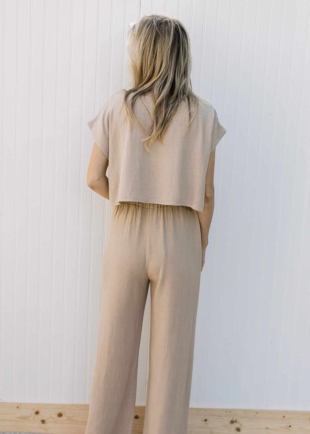 Back view of Model wearing an oatmeal set with wide leg pants and a cropped short sleeve top.