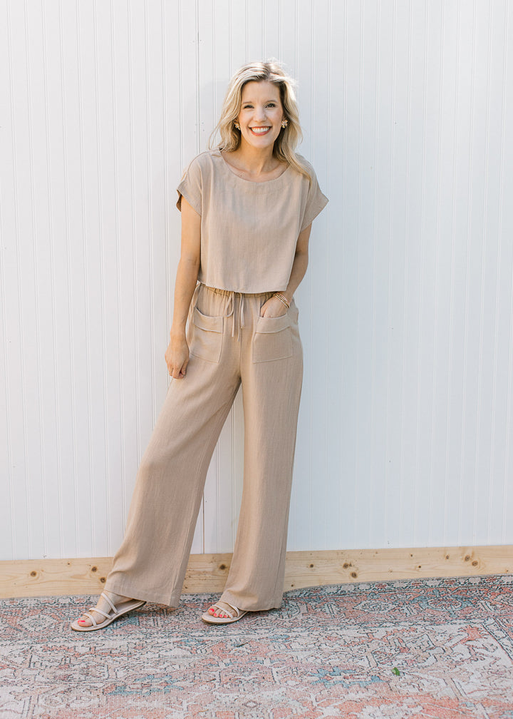 Model wearing an oatmeal set with wide leg pants with a tie closure and a cropped short sleeve top.