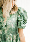 Close up view of layered short sleeve on a model wearing an above the knee green and cream dress.