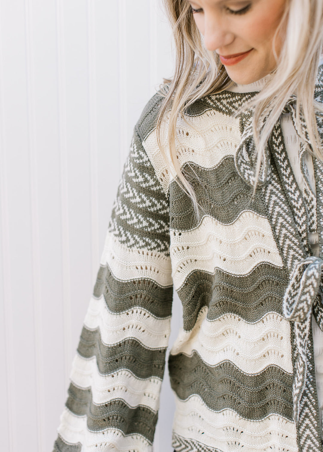 Close up of cream and olive wavy stripes on a cardigan with contrasting trim and tie closure.