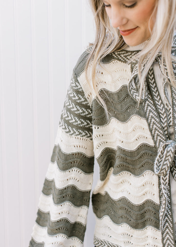 Close up of cream and olive wavy stripes on a cardigan with contrasting trim and tie closure.