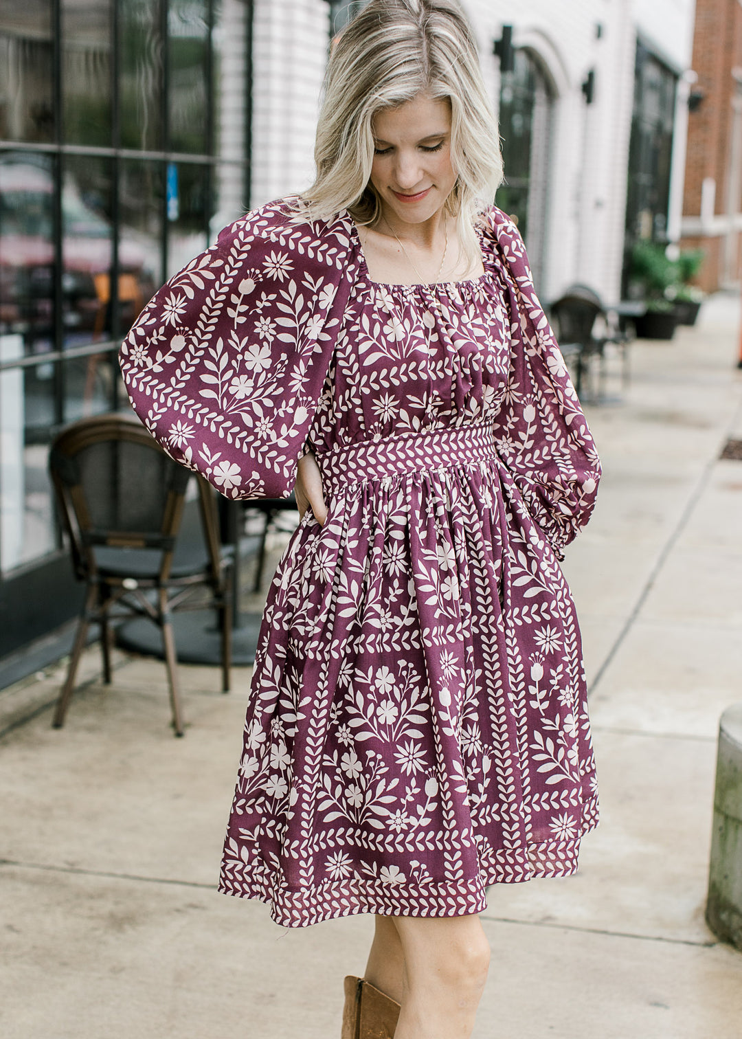 Model wearing a wine dress with cream floral, square neck, elastic back with tie and 3/4 sleeves.