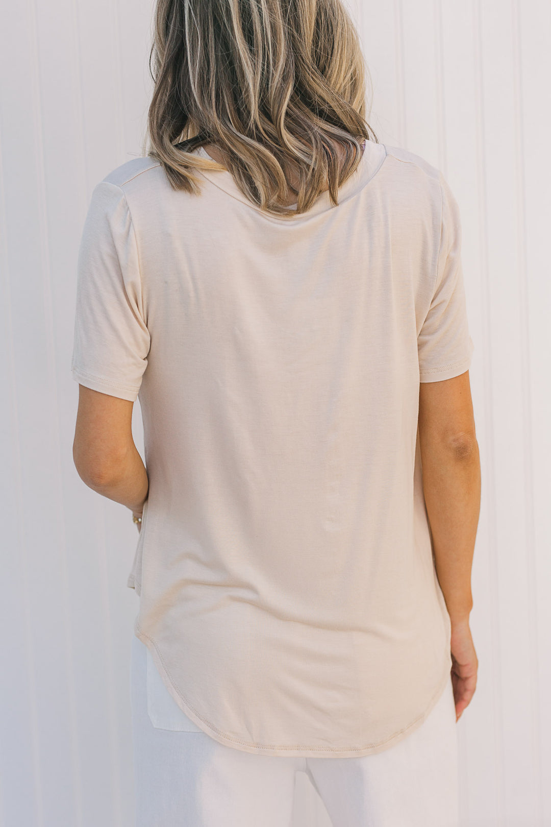 Back view of Model wearing a cream, short sleeve tee with bamboo material.