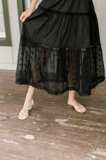 Close up of sheer bottom on a tiered overall black maxi dress. 