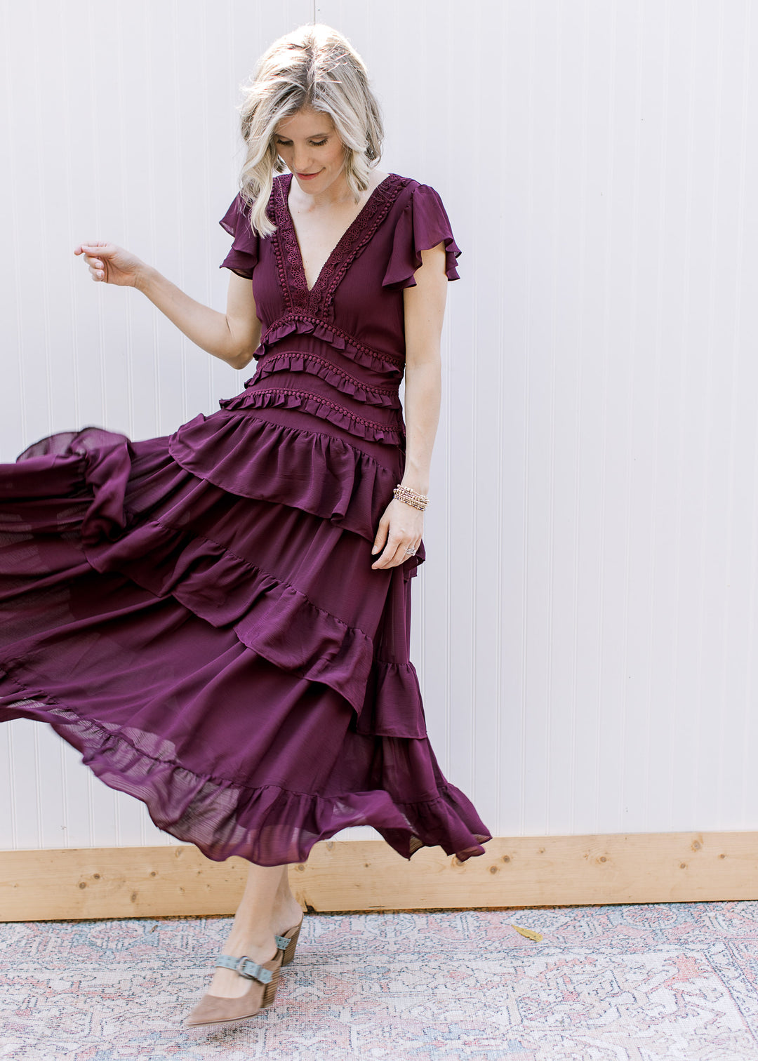  Model twirling in dark wine ruffle midi dress, showing flowing skirt tiers, flutter sleeves and sheer hem.