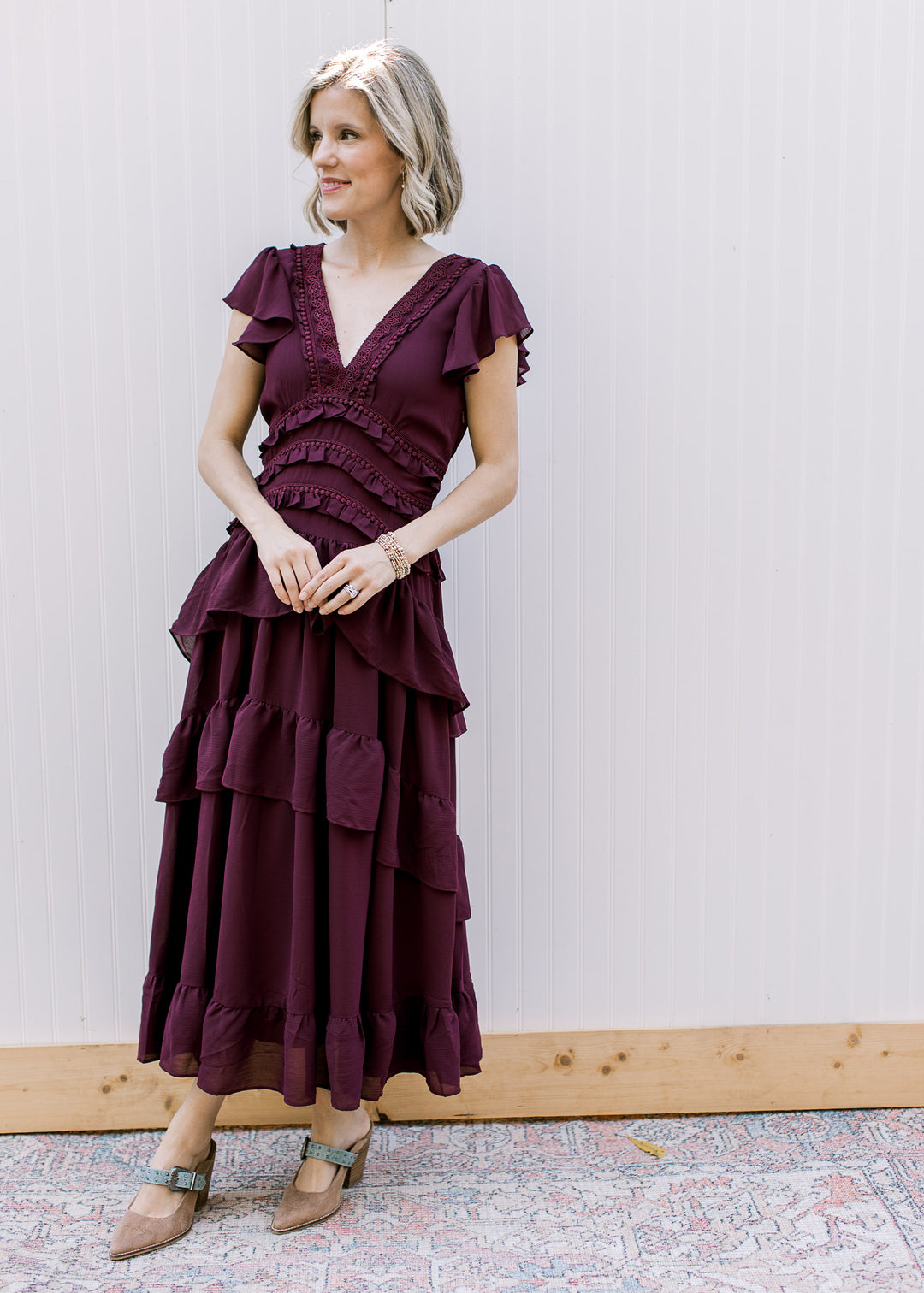  Front view of dark wine midi dress with lace-trimmed V-neckline, flutter sleeves and tiered ruffle skirt.