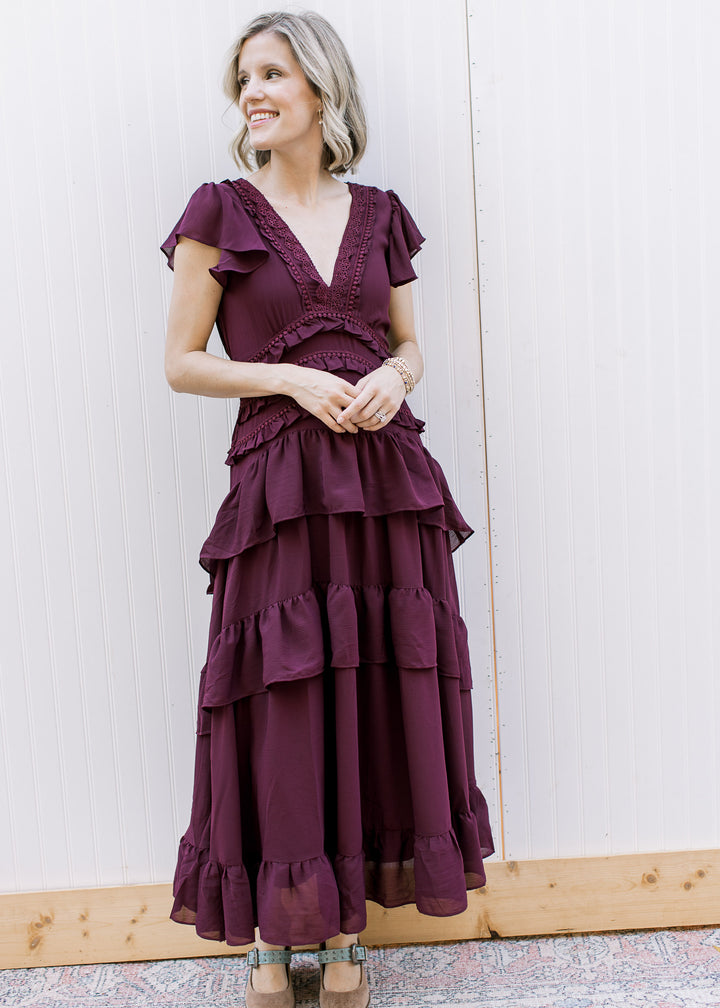 Full-length dark wine ruffle dress with lace neckline and tiered skirt, worn with taupe heels with blue straps.