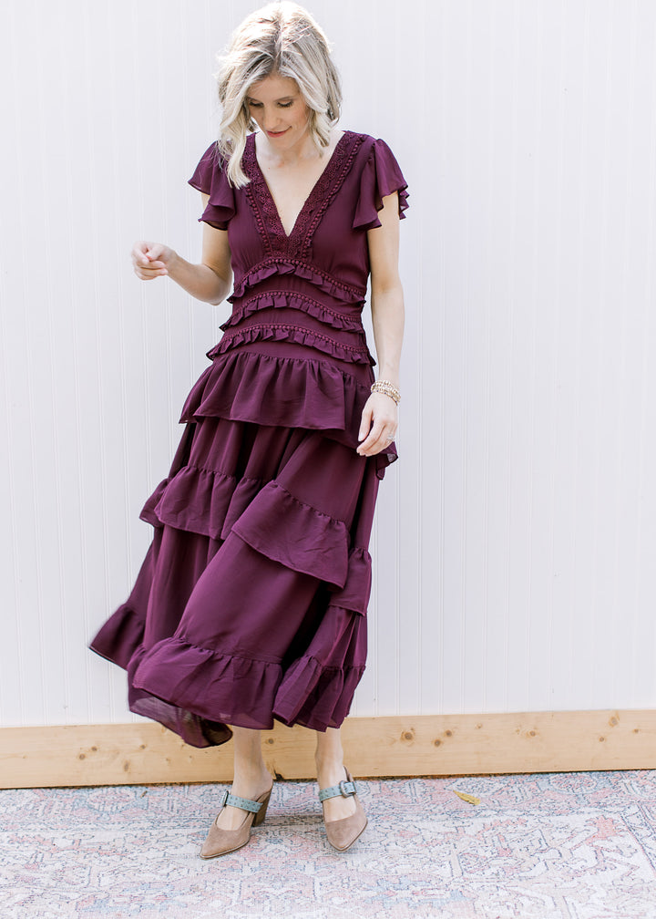 Dark wine tiered midi dress in motion, showing swaying ruffle skirt, defined waist and short flutter sleeves.