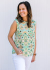 Model wearing white top with green and gold ikat pattern, sleeveless and a single button back.