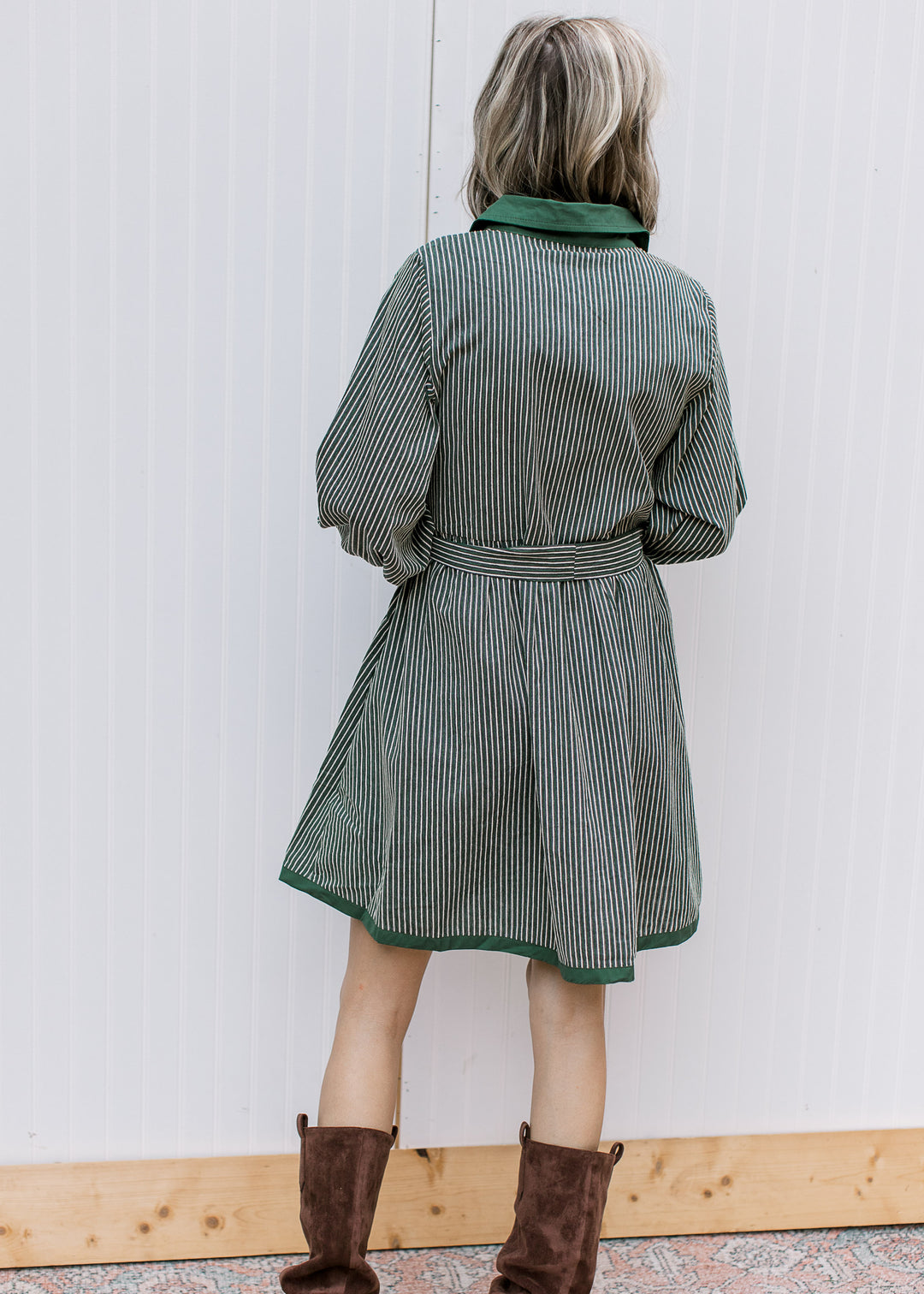 Back view of green and cream striped knee-length dress with matching waist belt, long sleeves and green hem trim.