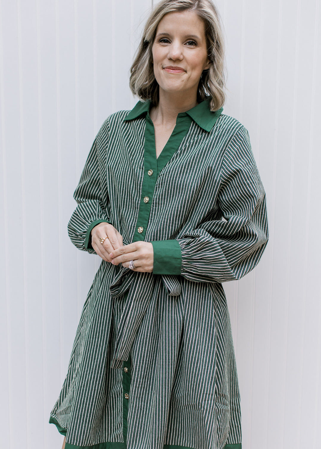 Green and cream striped dress with long gathered sleeves, green cuffs, gold buttons and matching belt tied in a bow.