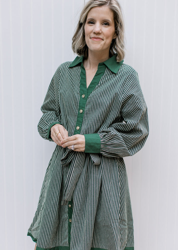 Green and cream striped dress with long gathered sleeves, green cuffs, gold buttons and matching belt tied in a bow.