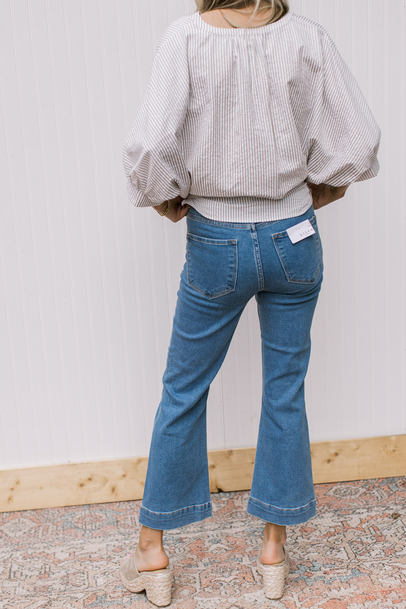 Back view of Model wearing high rise jeans with front patch pockets and ankle boot cut.