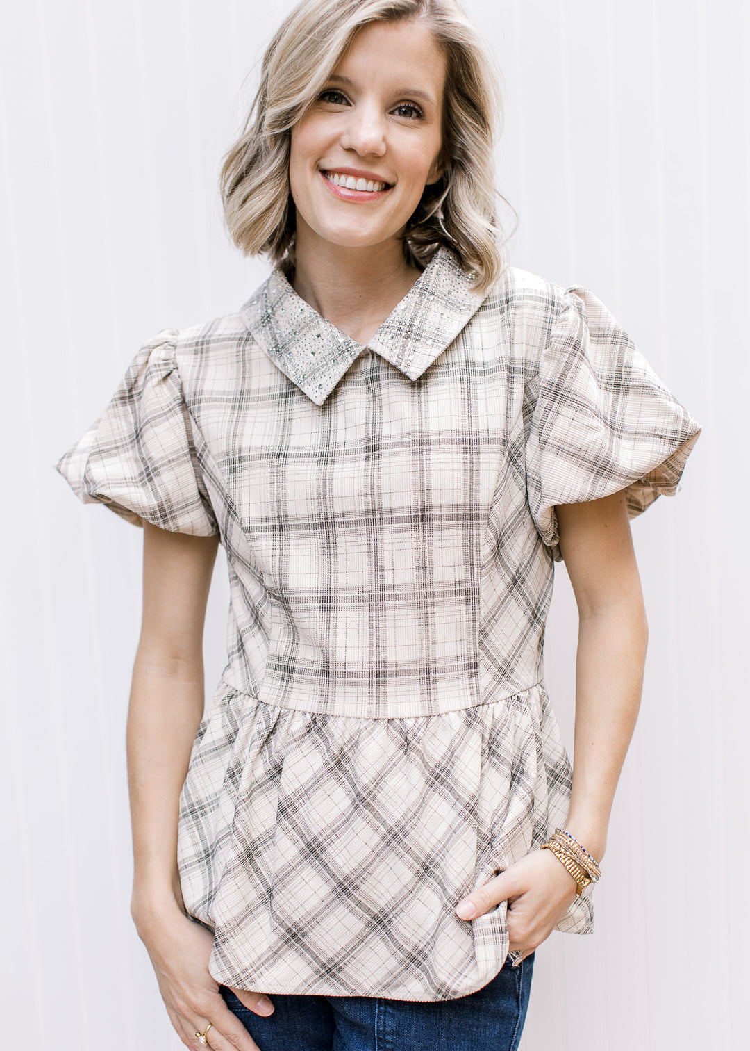 Front view of taupe plaid peplum top with jeweled collar, short bubble sleeves and fitted paneled bodice.
