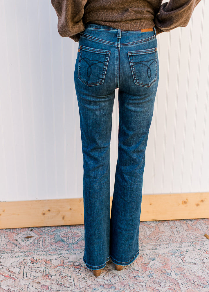 Back view of model wearing dark wash jeans with high-waisted tummy-control fit and a bootcut leg. 