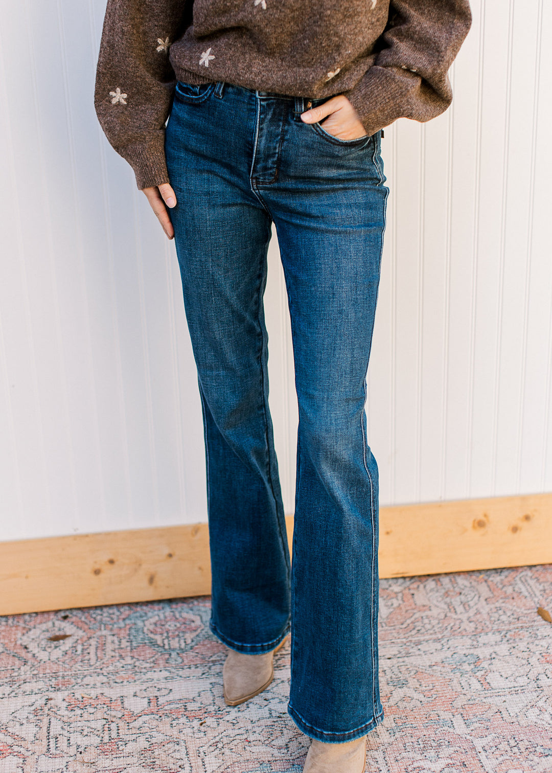 Model wearing dark wash jeans with high-waisted tummy-control fit and a bootcut leg. 
