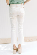 Back view of Model wearing bootcut white jeans with an amber color thread hem and 5 pockets. 