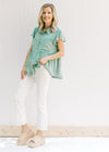 Model wearing a green top with bootcut white jeans with an amber color thread hem and 5 pockets. 