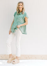 Model wearing a green top with bootcut white jeans with an amber color thread hem and 5 pockets. 