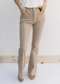 Model wearing hi-wasted, camel colored flare pants with extra tummy control. 
