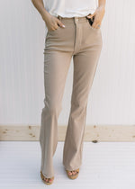 Model wearing hi-wasted, camel colored flare pants with extra tummy control. 