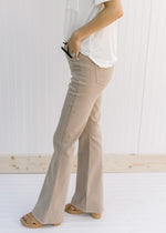 Side view of Model wearing hi-wasted, camel colored flare pants with extra tummy control. 