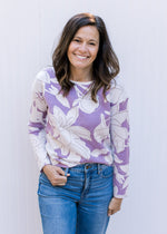 Model wearing a lavender boat neck sweater with cream flowers and metallic details. 