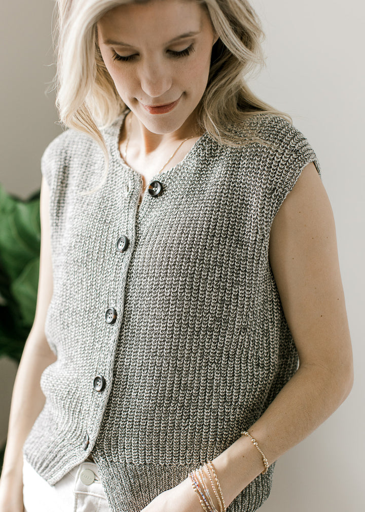 Model wearing a Black and white marled cap sleeve sweater with a button front and slight crop.