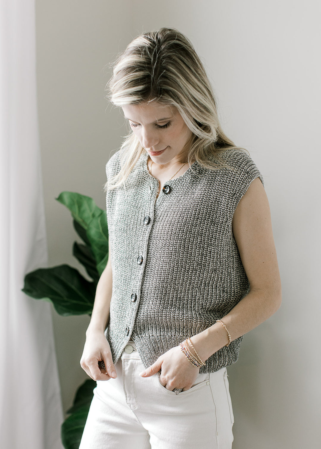 Model wearing a black and white marled cap sleeve sweater with buttons and slightly cropped fit.