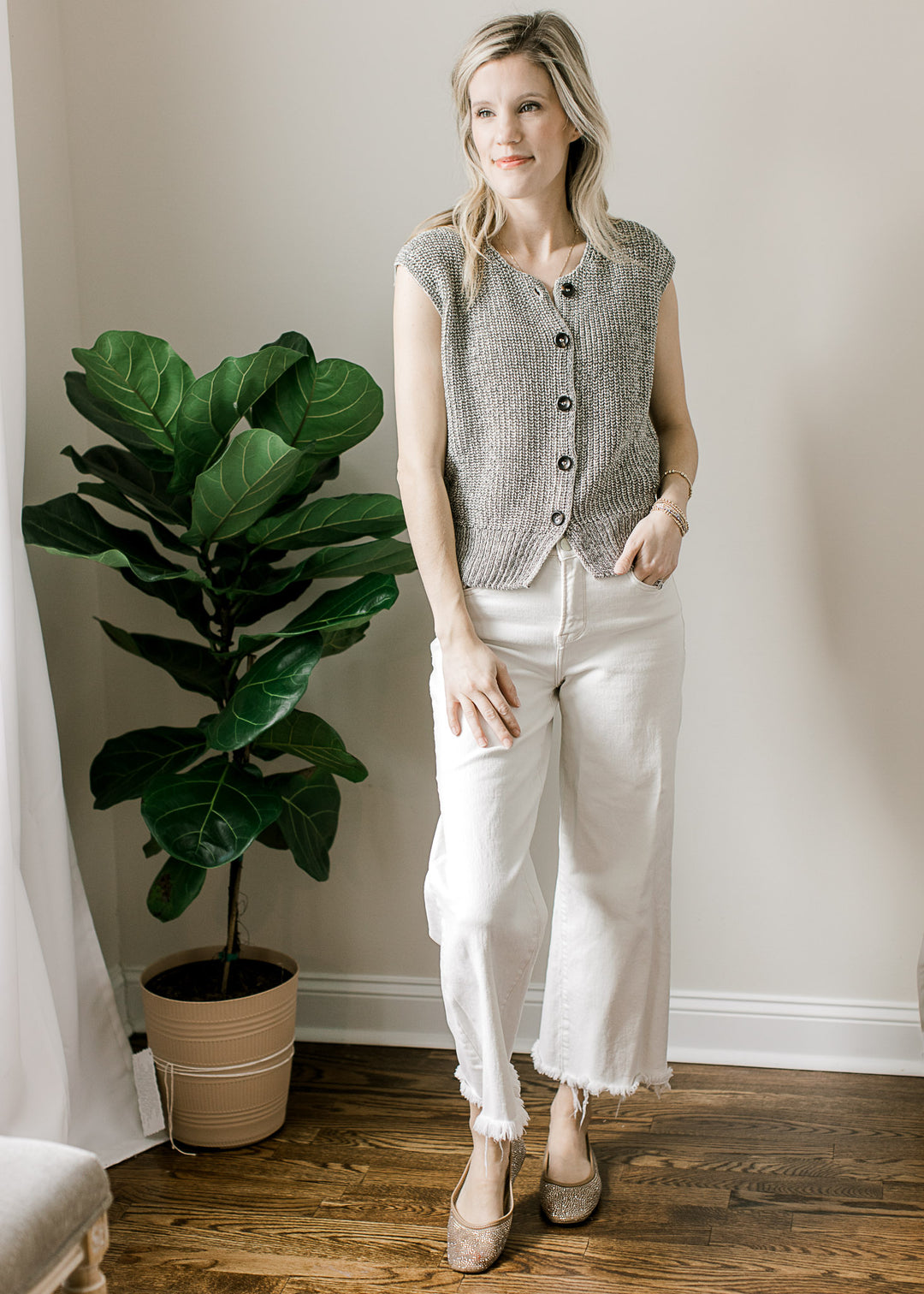 Model wearing white pants, flats and a Black and white marled cap sleeve sweater with buttons. 