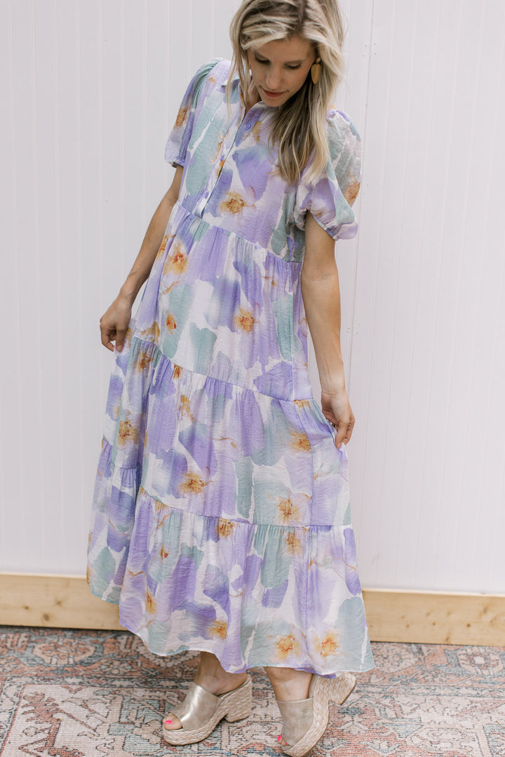 Model wearing a cream dress with watercolor flowers, tiered and bubble short sleeves. 