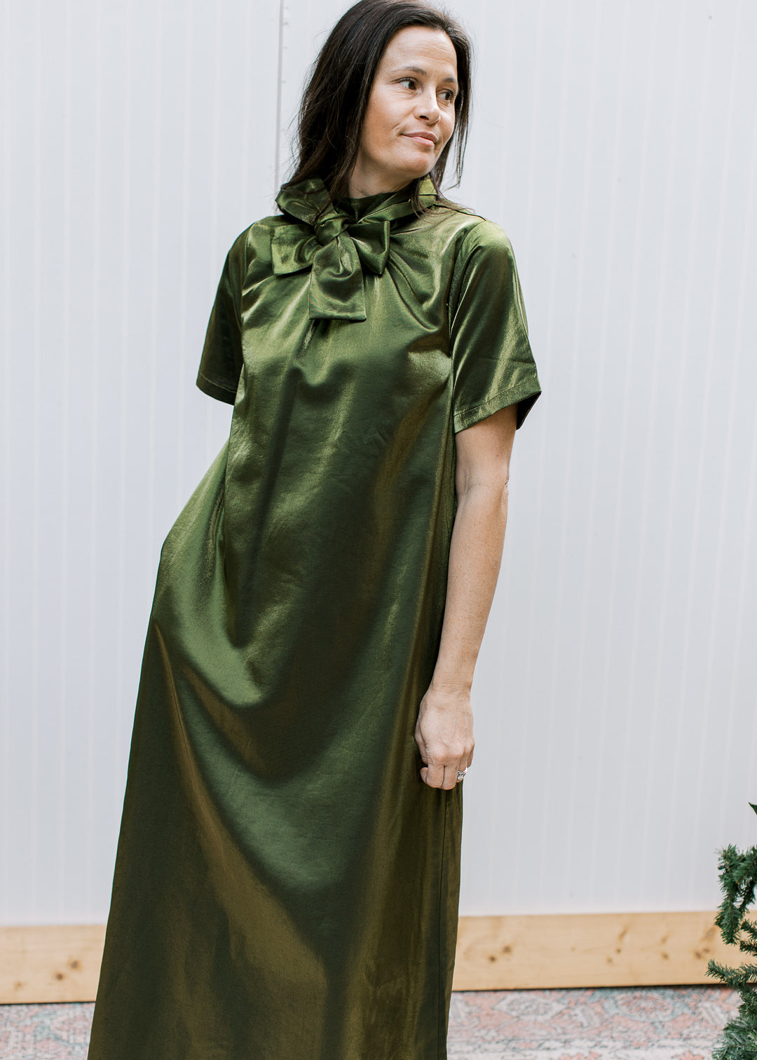  Model wearing olive tie-neck maxi dress with bow at the front, showing short sleeves, side pocket and fluid drape.