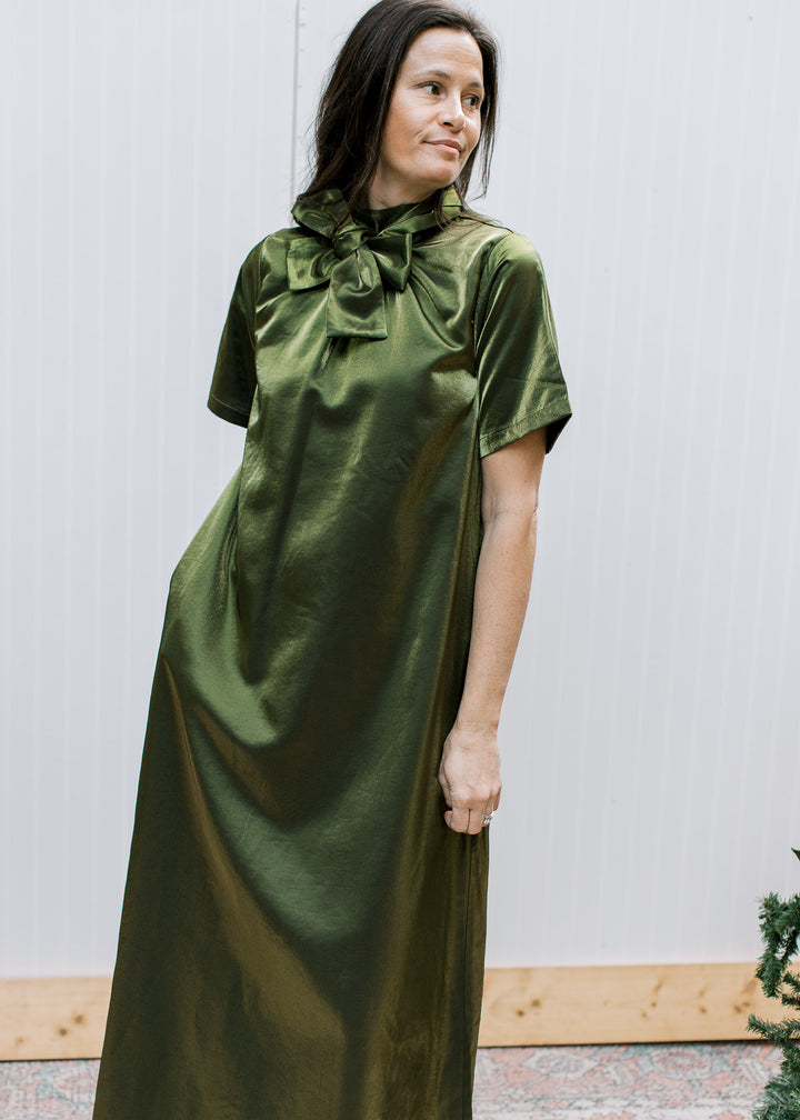  Model wearing olive tie-neck maxi dress with bow at the front, showing short sleeves, side pocket and fluid drape.