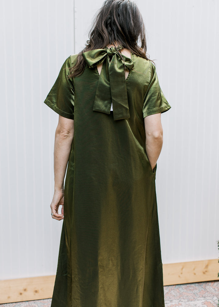 Back view of olive maxi dress showing oversized neckline bow, keyhole opening, short sleeves and flowing skirt.