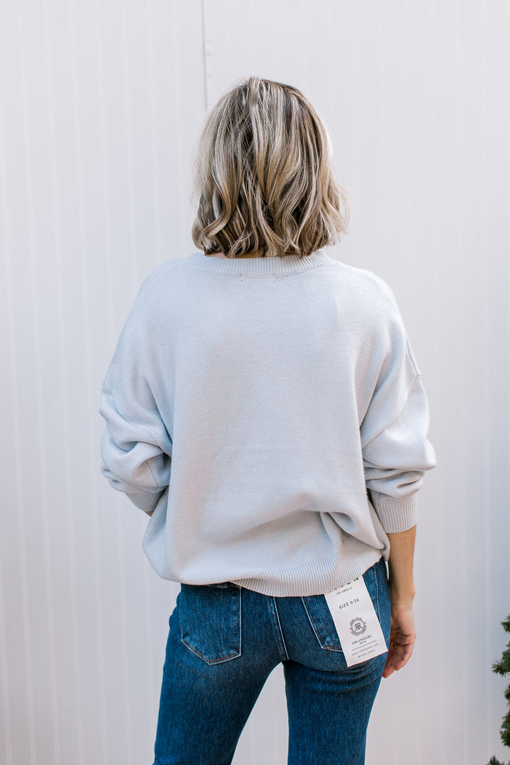 Back view of pale blue Ornament Christmas Sweater with plain knit, dropped shoulders, long sleeves and ribbed hem.