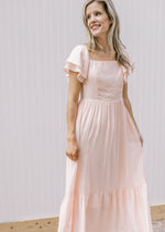 Model wearing a soft blush midi with a smocked back, short sleeves and a square neck.