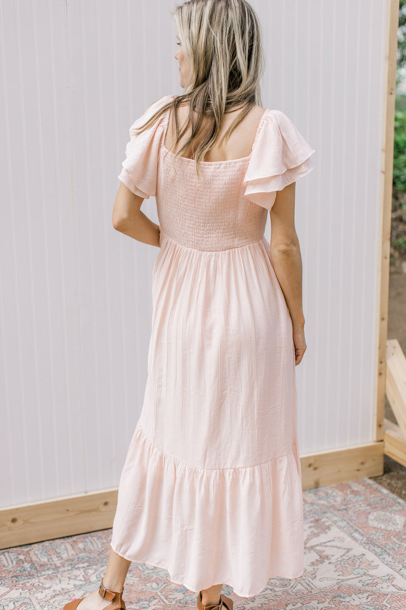 Back view of Model wearing a blush midi with layered sleeves a smocked back and a square neck.