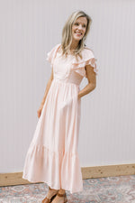 Model wearing a soft blush midi with layered ruffled sleeves and pockets.