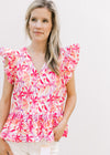 Model wearing a bold floral top with a v-neck, ruffle short sleeves and pleating detail.