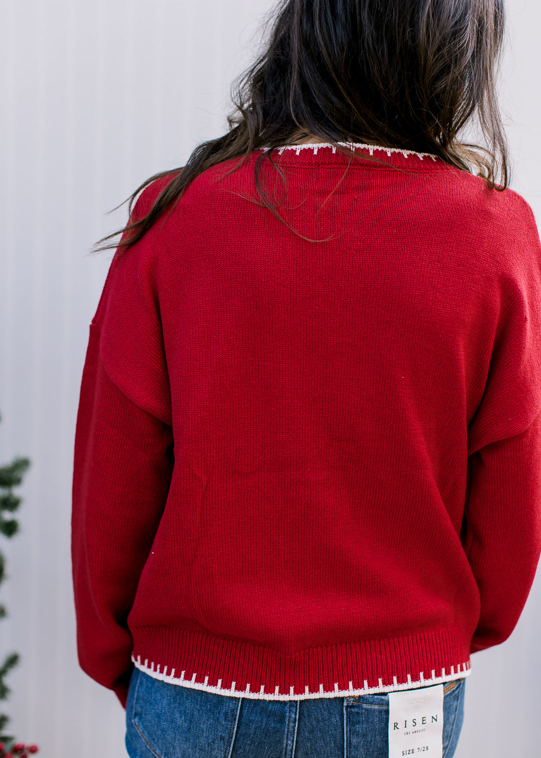 Back view of red Merry Sweater showing plain knit, dropped shoulders and cream blanket stitching at neckline and hem.