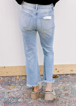 Back view of Model wearing light wash jeans with a frayed cropped hem and high waist.