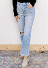 Model wearing light wash jeans with a frayed cropped hem, distressed knee and high waist.