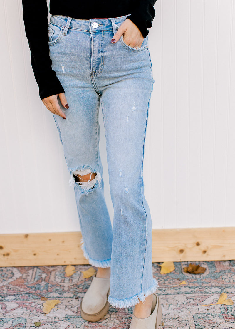 Model wearing clogs with light wash jeans with a frayed cropped hem and high waist.