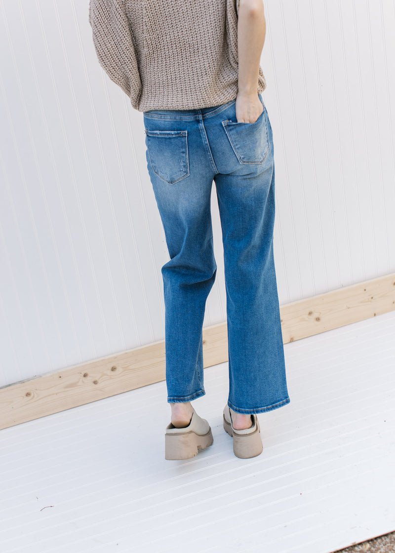 Back view of Model wearing medium washed relaxed straight jeans with a high rise and no destruction.
