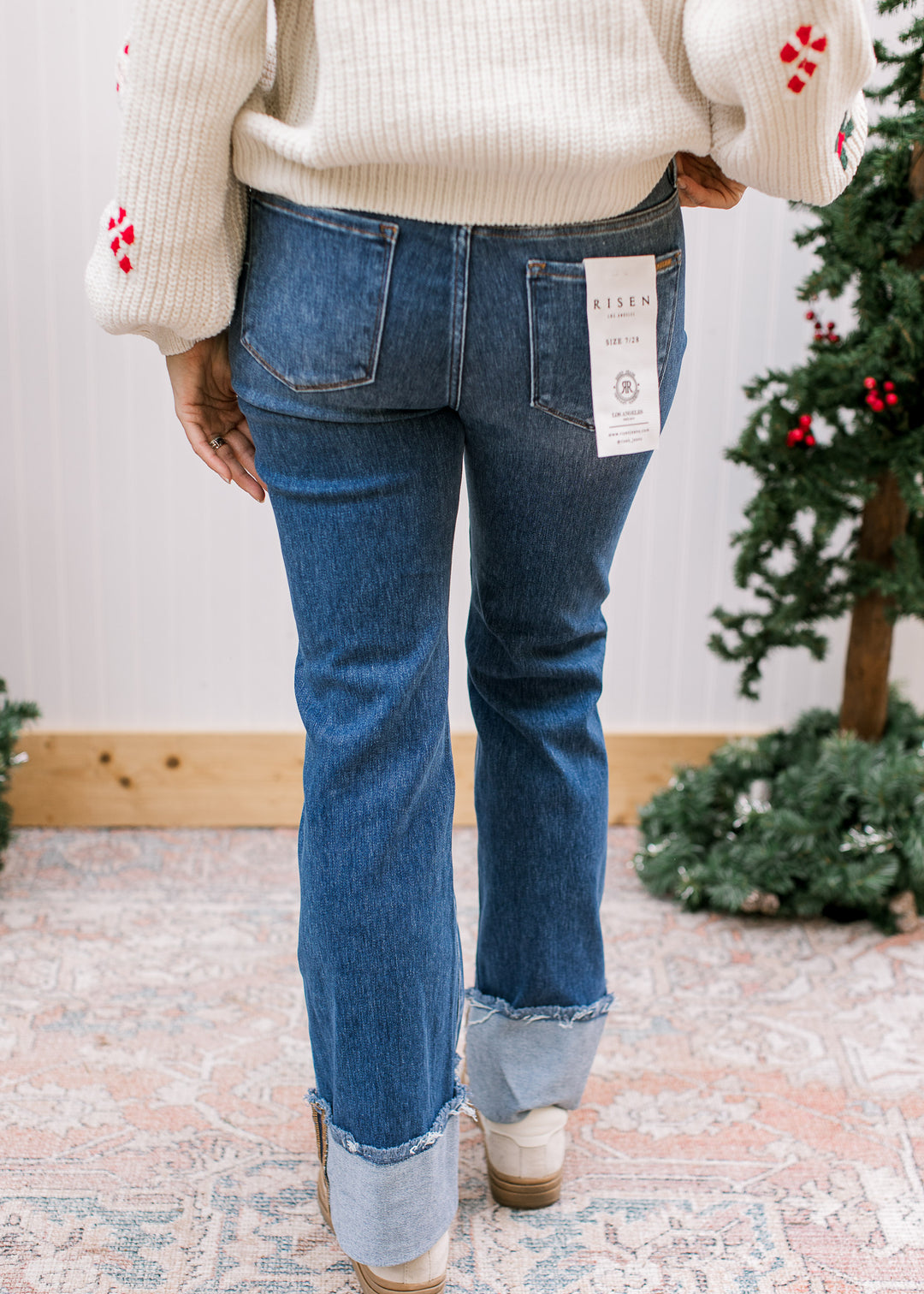 Back view of Risen blue flare jeans with patch pockets, fitted seat and wide turned-up cuffs with raw edges.