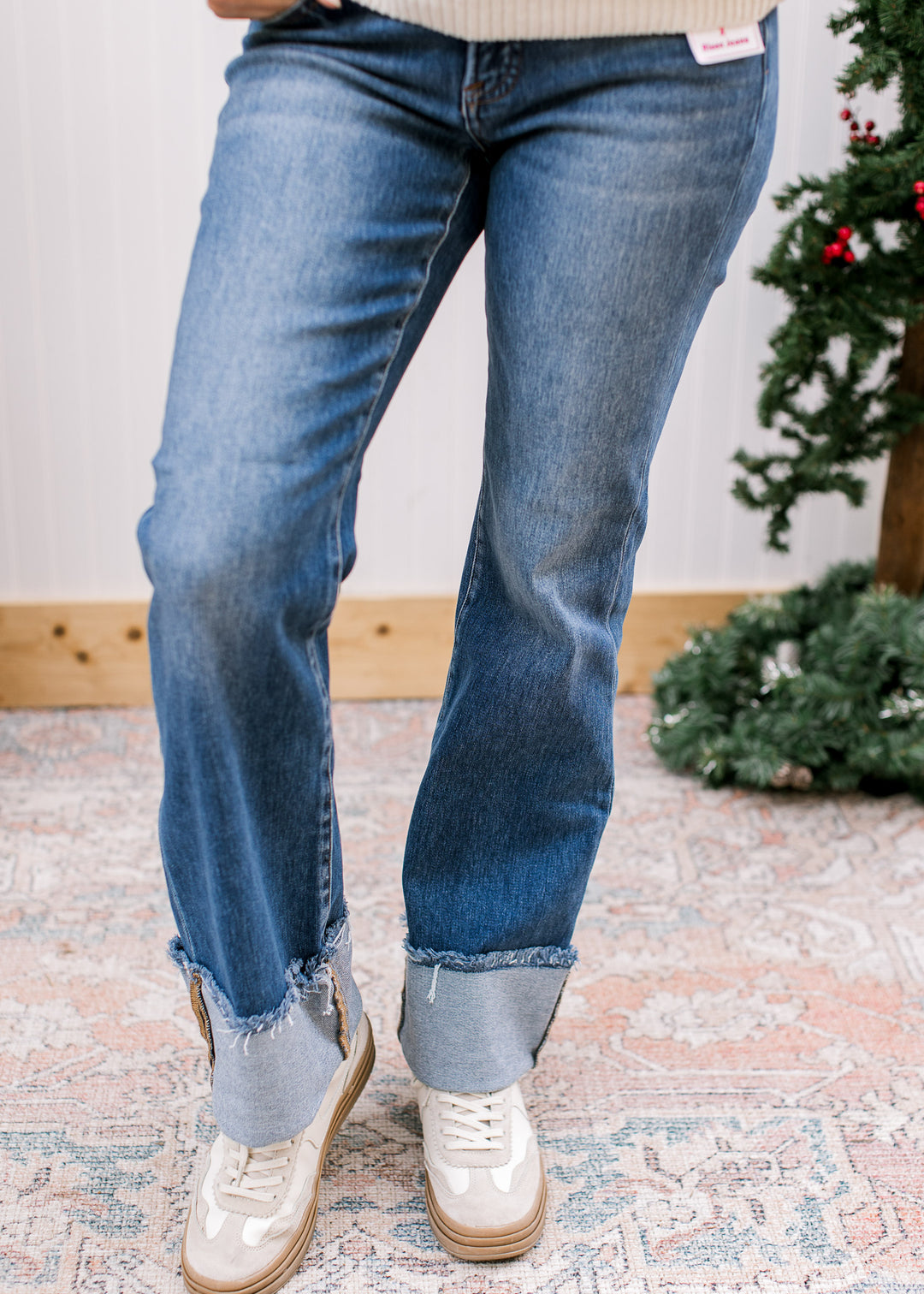 Close-up of Risen flare jeans showing faded thighs, flared lower legs and wide frayed cuffs, styled with sneakers.