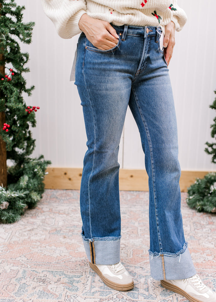 Risen tummy control flare jeans showing high waistband, front pockets and oversized contrast cuffs with frayed edges.