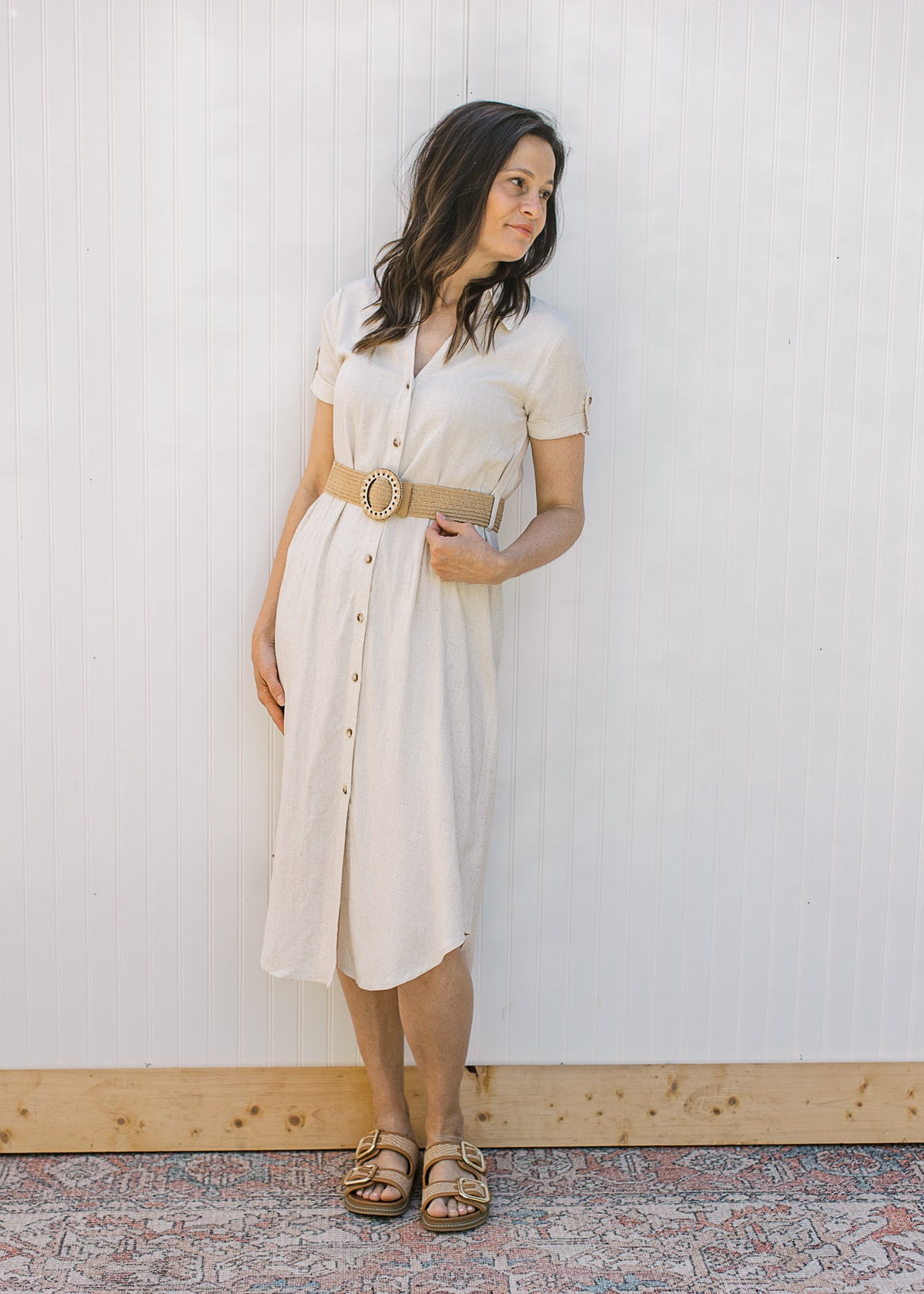 Model wearing sandals and a sandy linen dress with button front, collar, short sleeve and belt.