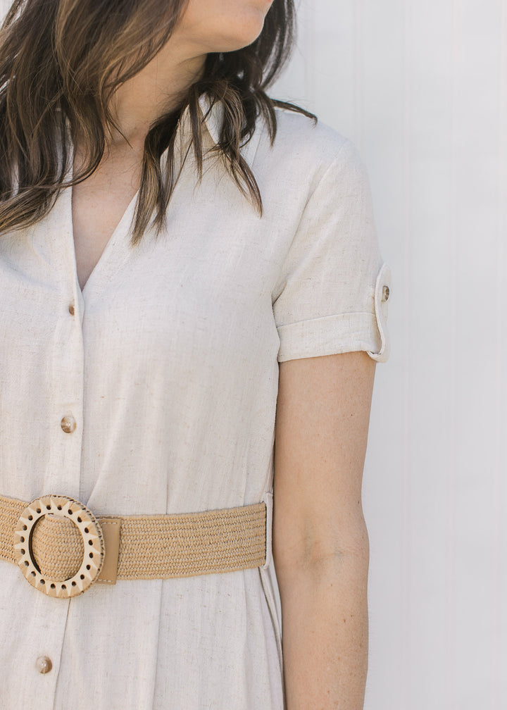 Close up of v-neck, button front and short sleeve with a button clasp on a sandy/cream midi.
